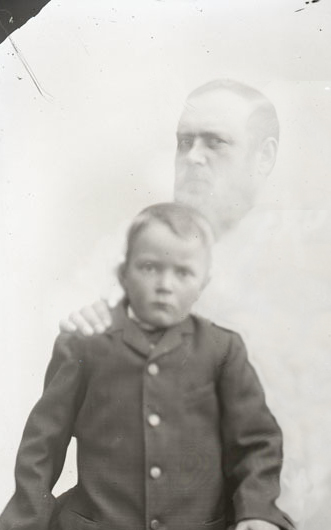 An old spirit-photograph portrait of a child with the ghostly face of a bearded man looming behind